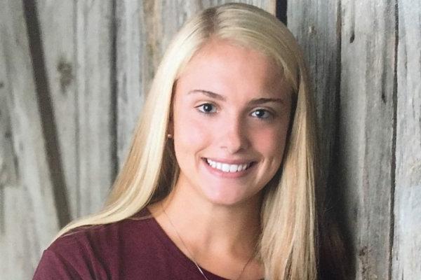 Isabelle LaBelle '23, stands in front of a wooden door, smiling.